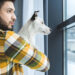 Man and dog looking out window.